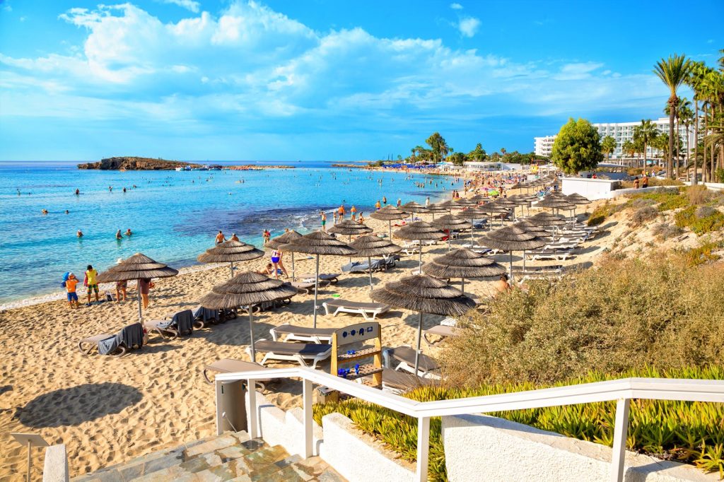 Picture of a digital nomad enjoying remote work in Cyprus with a laptop on a beach chair overlooking the ocean.Cyprus as a digital nomad destination. An image of a person working remotely with a laptop on a beach chair overlooking the Mediterranean Sea in Cyprus, showcasing the ideal work-life balance that can be achieved in this location.